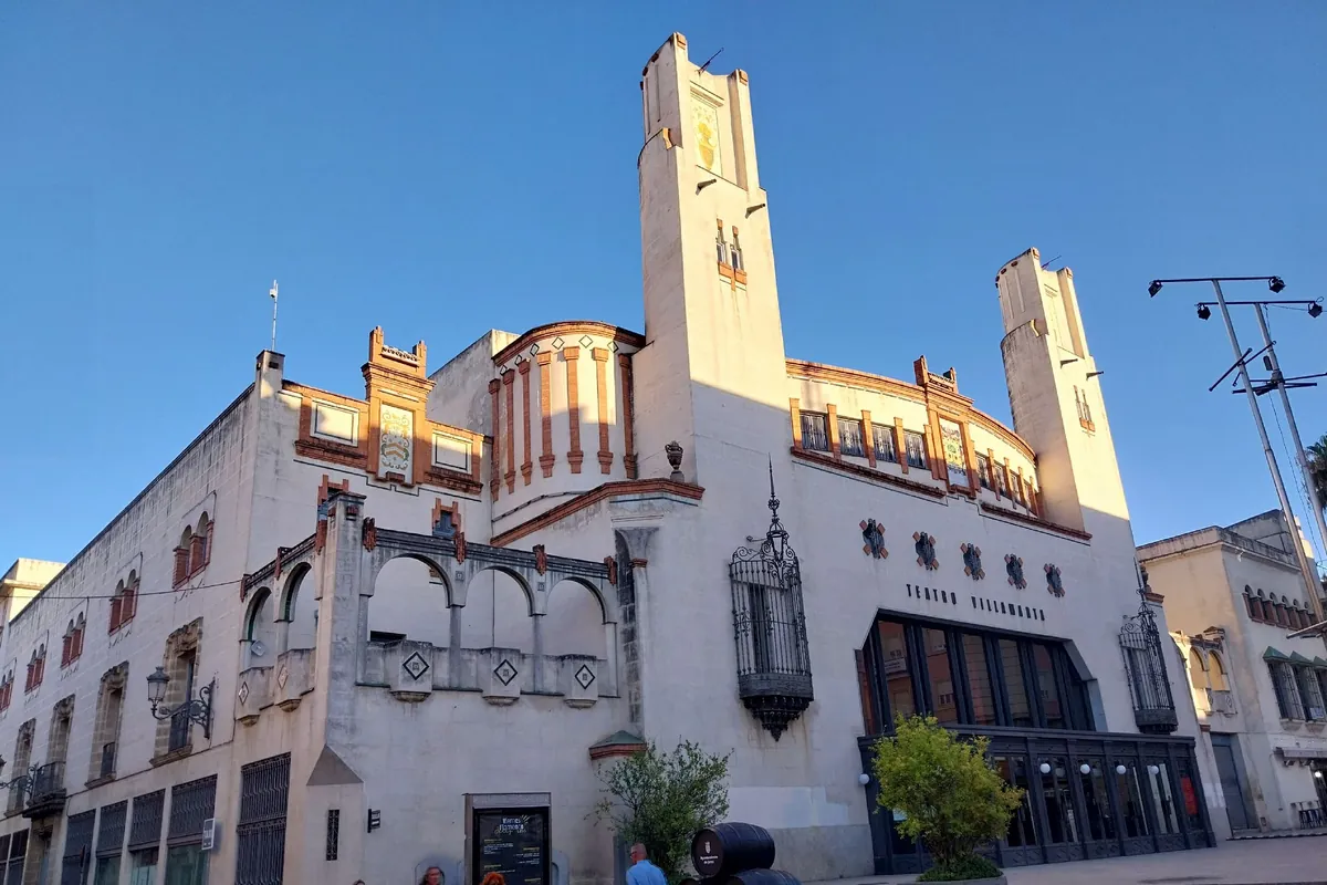 Krémovo-tehlová fasáda Teatro Villamarta v Jereze s dvoma vysokými vežami, oblúkovými oknami a modrou oblohou